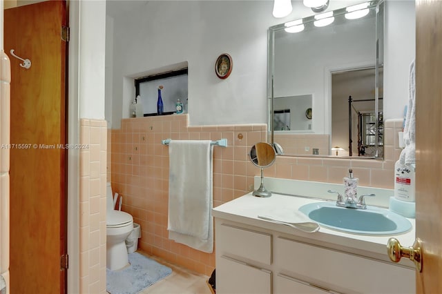 bathroom with vanity, tile walls, and toilet