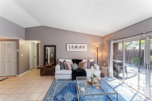 living area featuring vaulted ceiling, light tile patterned flooring, and baseboards