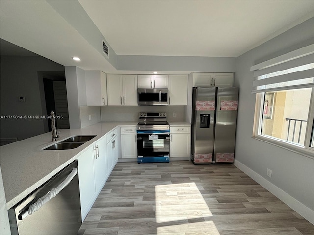 kitchen featuring light wood-type flooring, stainless steel appliances, sink, and white cabinets