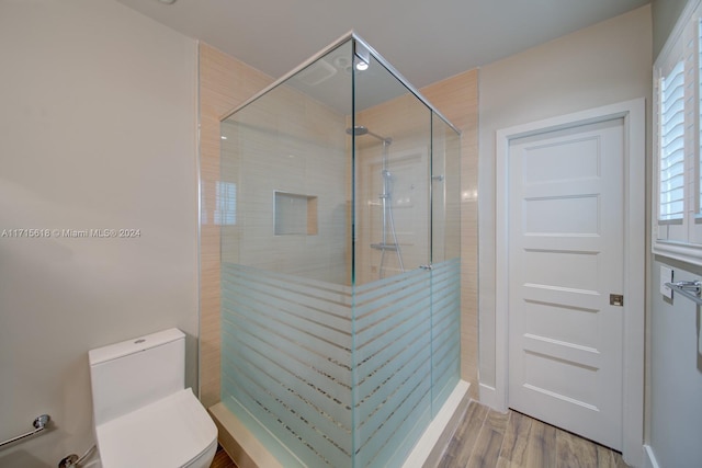 bathroom with toilet, an enclosed shower, and hardwood / wood-style flooring