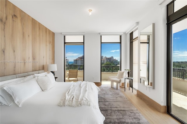 bedroom with expansive windows, light wood finished floors, access to outside, and multiple windows