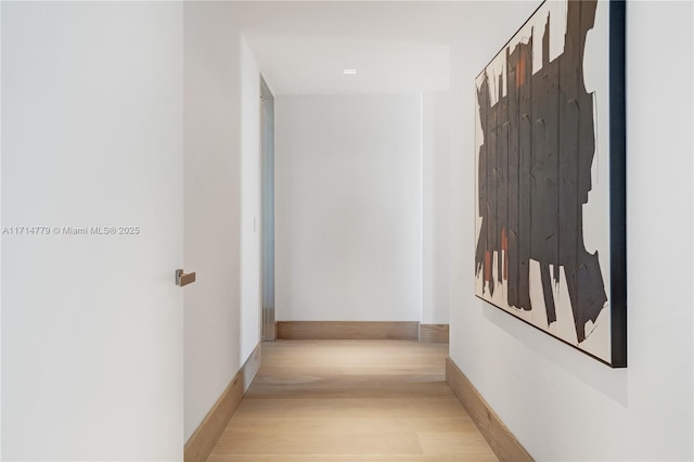 hall with light wood-style flooring and baseboards