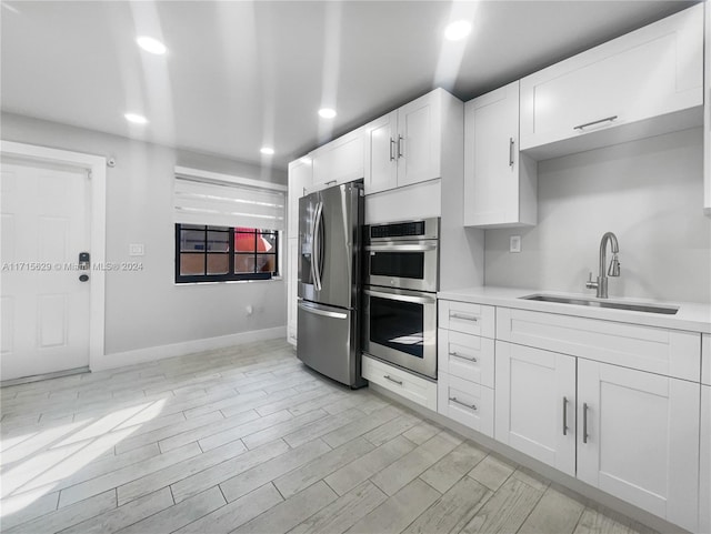 kitchen with stainless steel appliances, white cabinetry, and sink