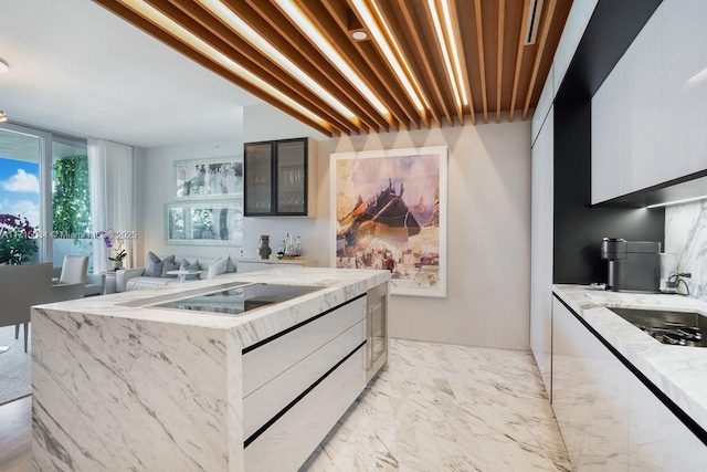 kitchen with white cabinets, a center island, light stone countertops, and stovetop