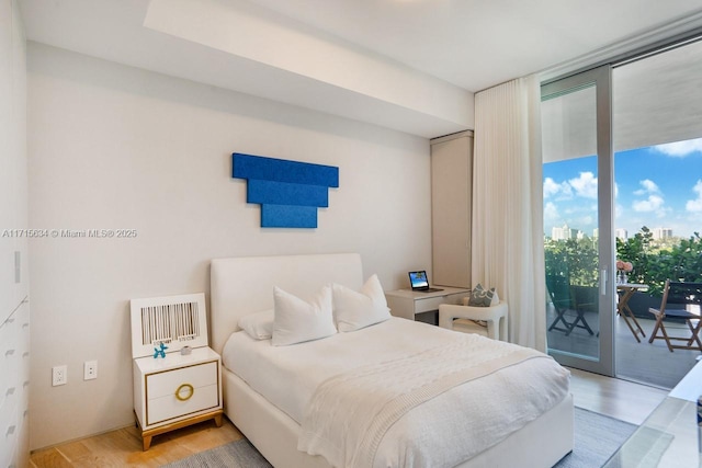 bedroom with access to exterior, hardwood / wood-style floors, and a wall of windows