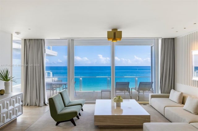 living room featuring a healthy amount of sunlight, a water view, and a wall of windows