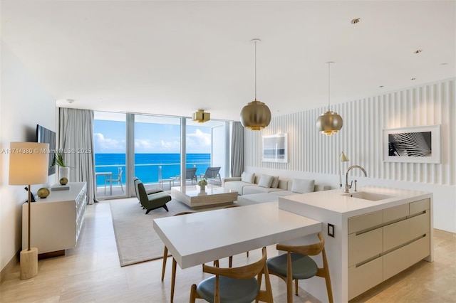 kitchen with floor to ceiling windows, sink, decorative light fixtures, a center island with sink, and cream cabinetry