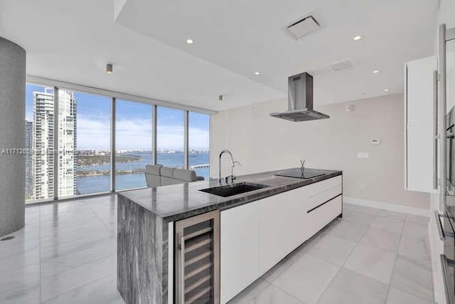 kitchen featuring a water view, wall chimney range hood, sink, wine cooler, and white cabinetry