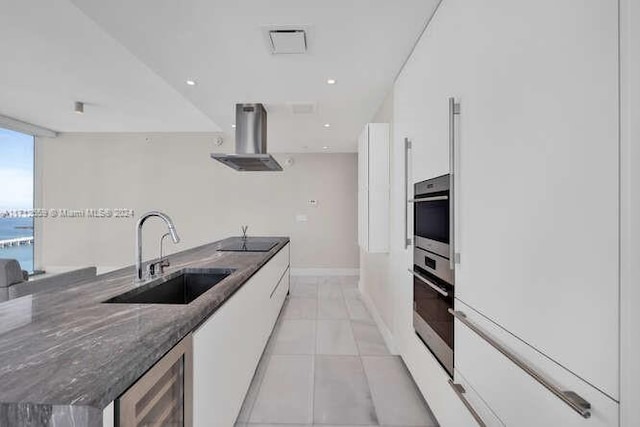 kitchen featuring extractor fan, sink, white cabinetry, and stainless steel oven