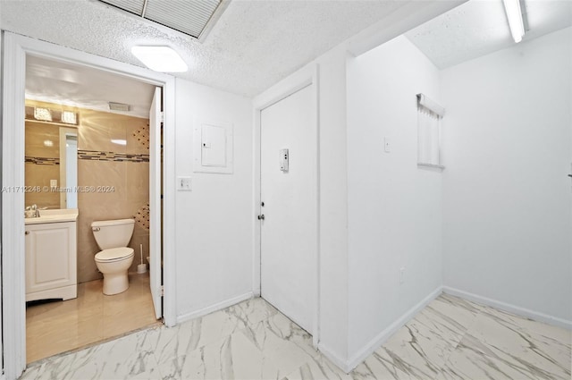 bathroom featuring vanity, a textured ceiling, electric panel, and toilet