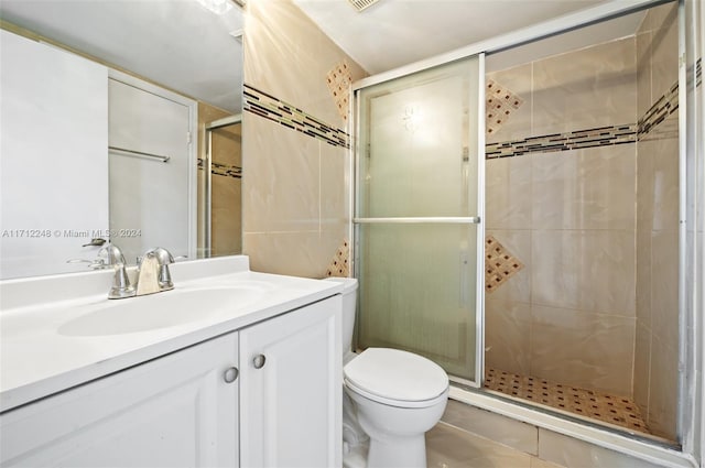 bathroom with tile patterned floors, vanity, toilet, and a shower with door