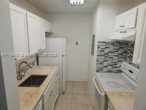 kitchen with electric stove, sink, white cabinets, and range hood