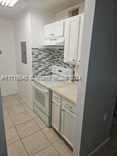 kitchen featuring light tile patterned floors, ventilation hood, electric panel, stainless steel electric stove, and white cabinets