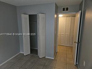 1153 Lake Victoria Dr Unit J, West Palm Beach, FL 33411 - unfurnished bedroom with tile patterned floors, baseboards, and visible vents