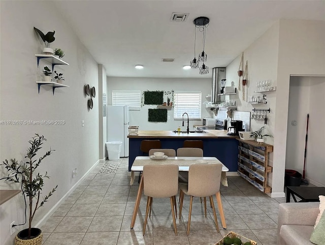 kitchen featuring visible vents, light tile patterned flooring, a sink, and freestanding refrigerator