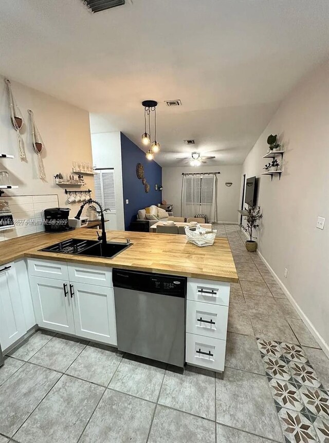 kitchen with wooden counters, white cabinets, stainless steel dishwasher, and hanging light fixtures