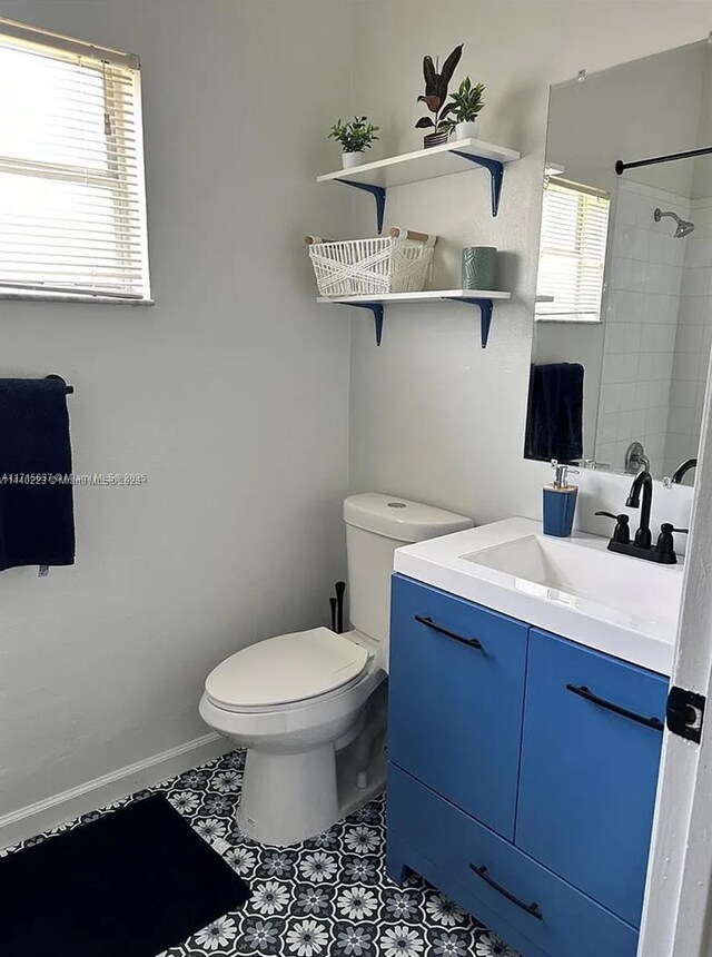 bathroom featuring a tile shower, tile patterned floors, vanity, and toilet