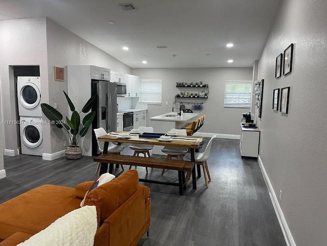 dining area with stacked washer and dryer, dark wood-type flooring, and sink