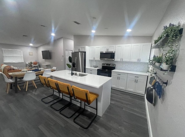 kitchen featuring white cabinets, appliances with stainless steel finishes, dark hardwood / wood-style flooring, and tasteful backsplash