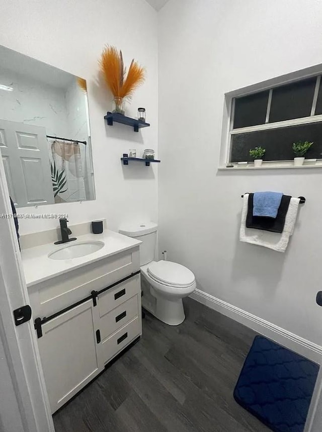 bathroom with hardwood / wood-style flooring, vanity, toilet, and walk in shower