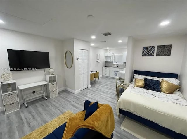 bedroom featuring a closet, sink, and light hardwood / wood-style flooring