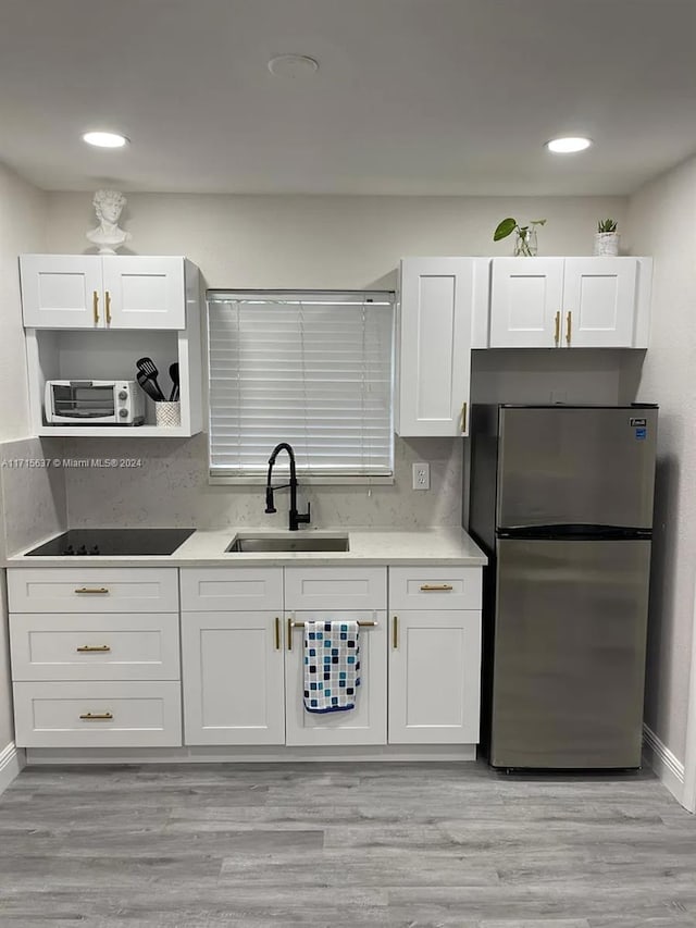 kitchen featuring stainless steel fridge, backsplash, sink, light hardwood / wood-style flooring, and white cabinets