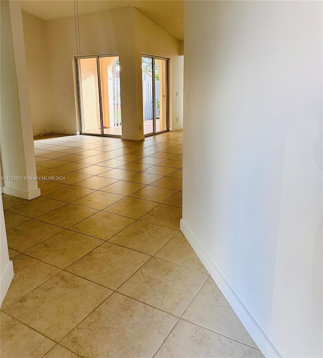 corridor with lofted ceiling and light tile patterned floors