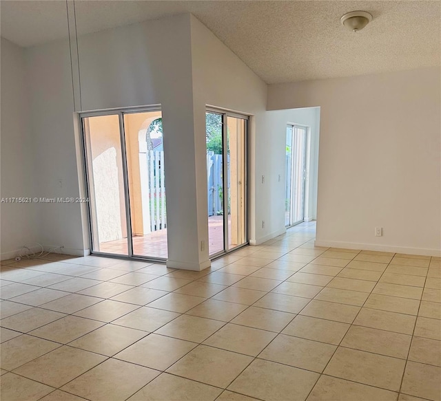 empty room with light tile patterned floors, a textured ceiling, and high vaulted ceiling