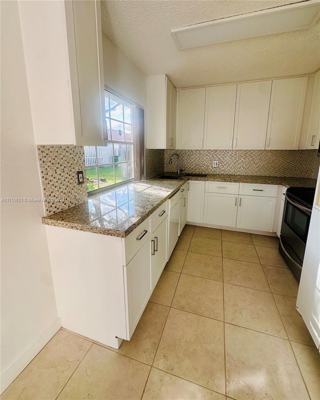 kitchen with black electric range, light tile patterned flooring, backsplash, a textured ceiling, and white cabinets