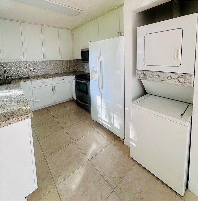 kitchen featuring black / electric stove, white cabinets, white fridge with ice dispenser, tasteful backsplash, and stacked washer / drying machine