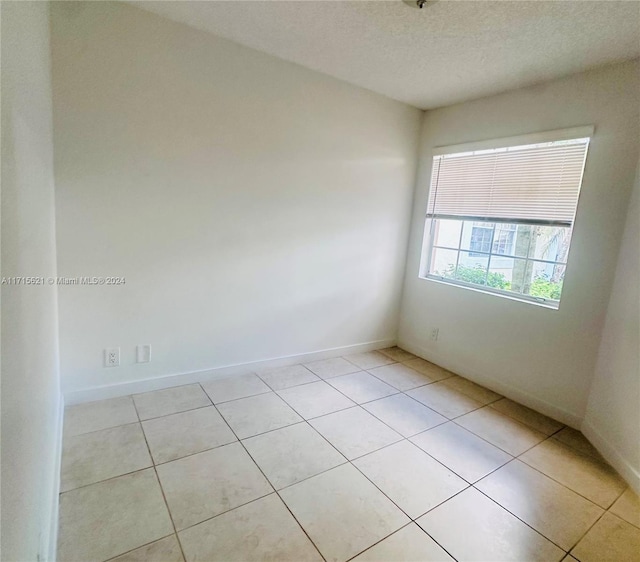 tiled empty room featuring a textured ceiling