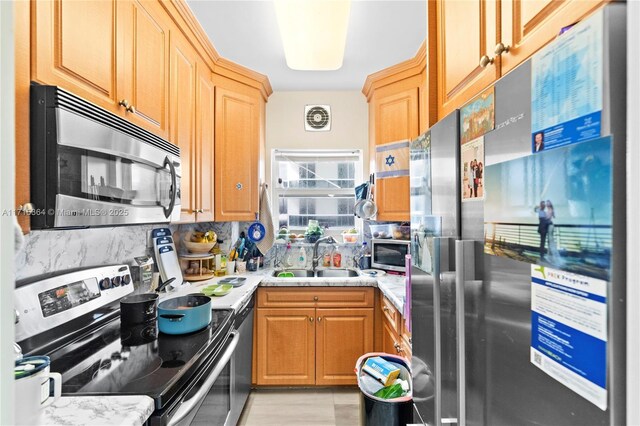 kitchen with sink, light stone countertops, and appliances with stainless steel finishes