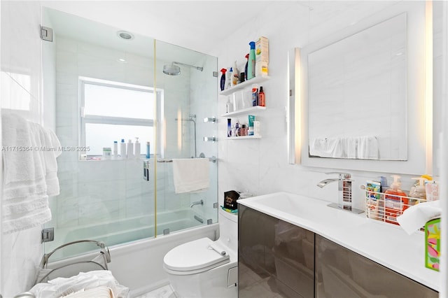 full bathroom featuring toilet, tile walls, enclosed tub / shower combo, and vanity