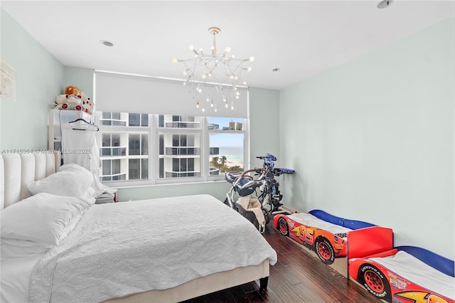 bedroom featuring a notable chandelier, dark hardwood / wood-style floors, and a water view