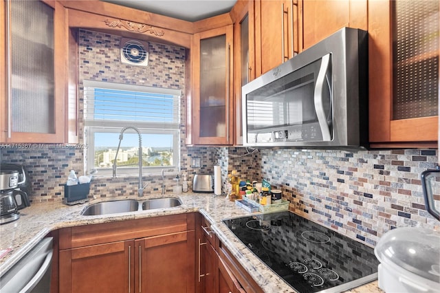 kitchen featuring appliances with stainless steel finishes, tasteful backsplash, light stone counters, and sink