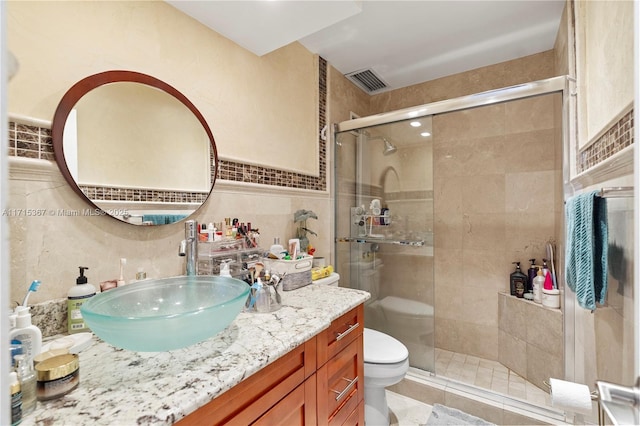 bathroom featuring vanity, toilet, tile walls, and walk in shower