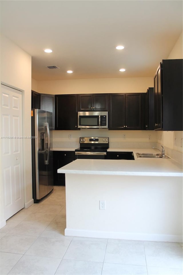 kitchen featuring kitchen peninsula, sink, light tile patterned floors, and stainless steel appliances