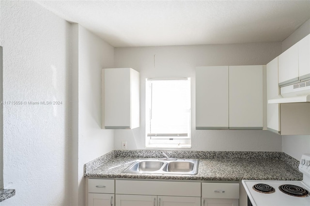 kitchen with sink, white cabinets, and range