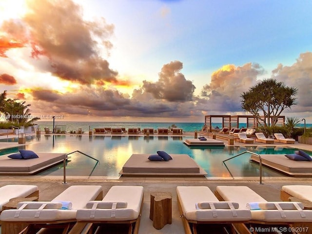 pool at dusk featuring a water view