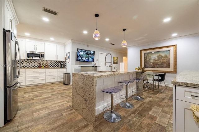 3111 N 52nd Ave, Hollywood, FL 33021 - kitchen with appliances with stainless steel finishes, ornamental molding, backsplash, a kitchen breakfast bar, and white cabinetry