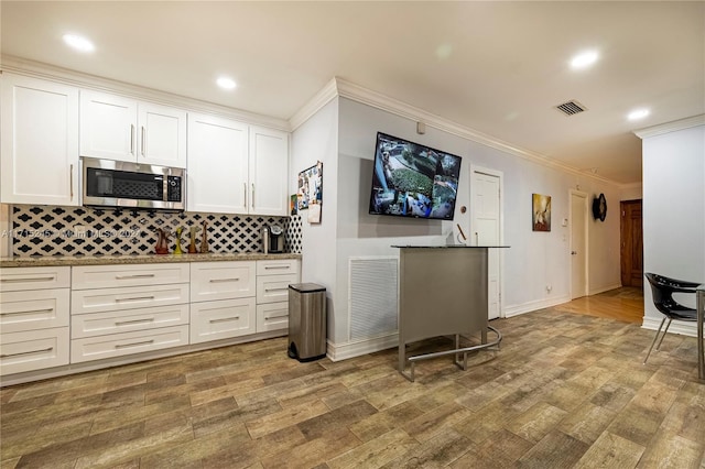 3111 N 52nd Ave, Hollywood, FL 33021 - kitchen featuring stainless steel microwave, wood finished floors, white cabinets, ornamental molding, and recessed lighting