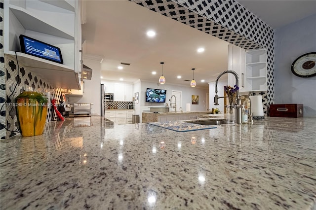 interior details featuring stone counters, decorative backsplash, ornamental molding, decorative light fixtures, and white cabinetry