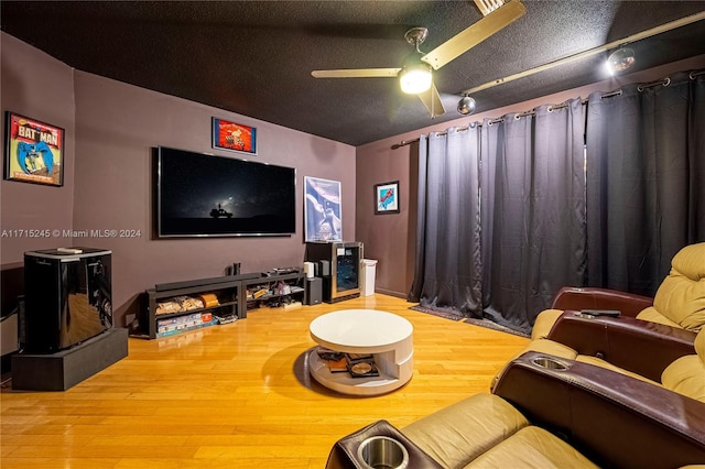 cinema room with ceiling fan, wood-type flooring, and a textured ceiling