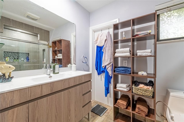 bathroom with wood-type flooring, vanity, toilet, and an enclosed shower