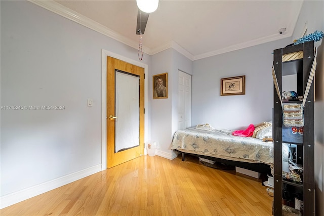 bedroom featuring ceiling fan, a closet, wood-type flooring, and ornamental molding