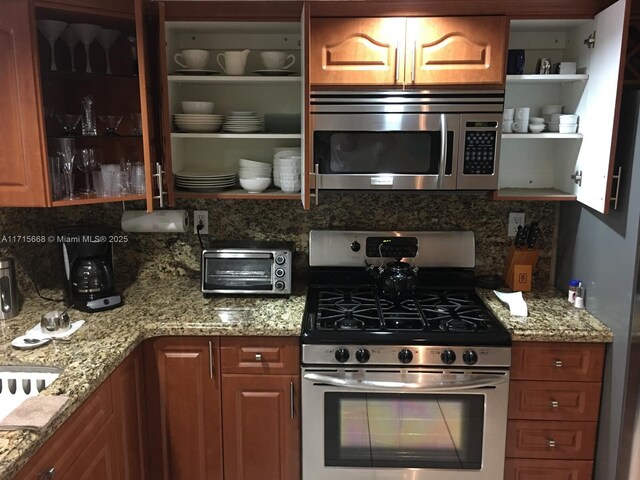 kitchen featuring appliances with stainless steel finishes, backsplash, and light stone counters