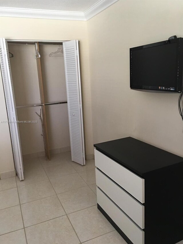 tiled bedroom featuring ornamental molding and a closet