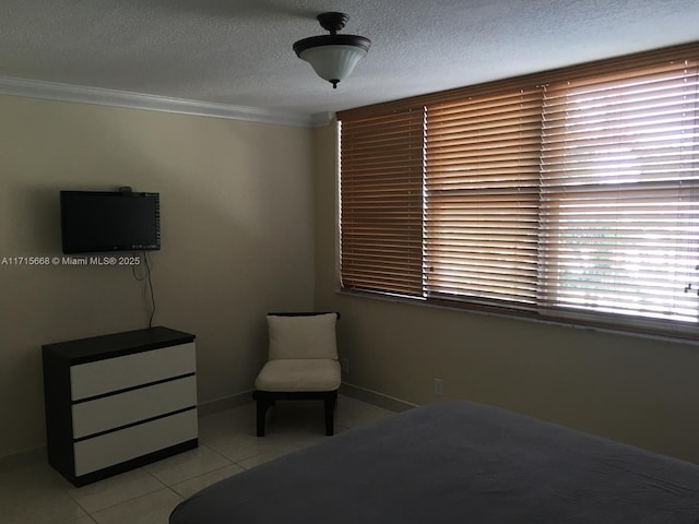 bedroom featuring light tile patterned floors, crown molding, baseboards, and a textured ceiling