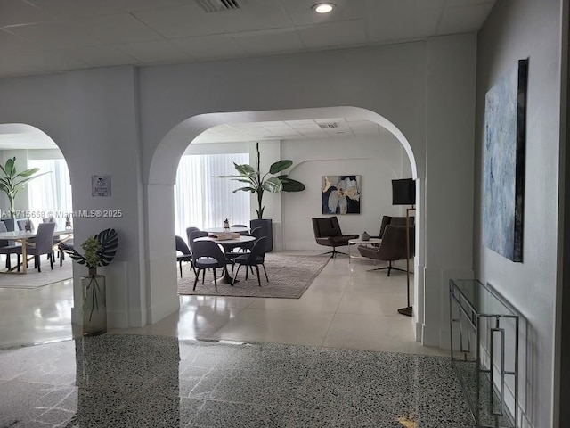 hall featuring arched walkways and a paneled ceiling