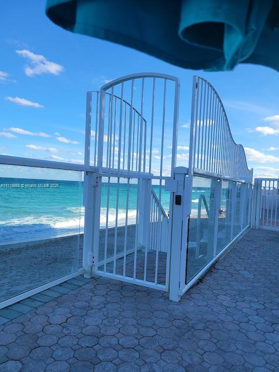 view of gate with a beach view and a water view